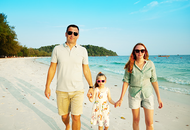 Happy family: Mom, dad and daughter walk along the Longest Beach of Koh Rong Island in Cambodia